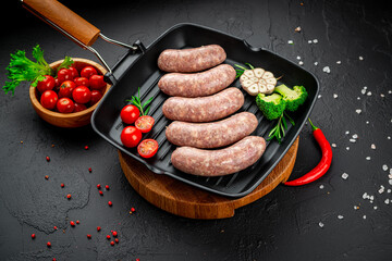Raw homemade sausages with vegetables on a grill pan
