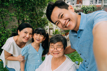 Group of multi-generational Asian family taking a selfie photo together in backyard garden and smiling with happiness. Family spending time and love concept - 504254808