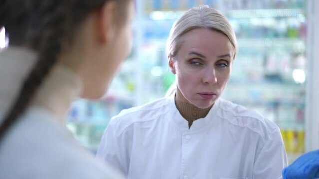 Dissatisfied angry pharmacy manager arguing with worker indoors. Portrait of furious unsatisfied Caucasian woman yelling talking with colleague in drugstore. Conflict and stress concept