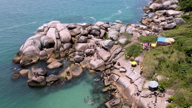 Aerial drone image of rocky mountain, coast of stones near paradise beach with people diving and having fun in natural pools