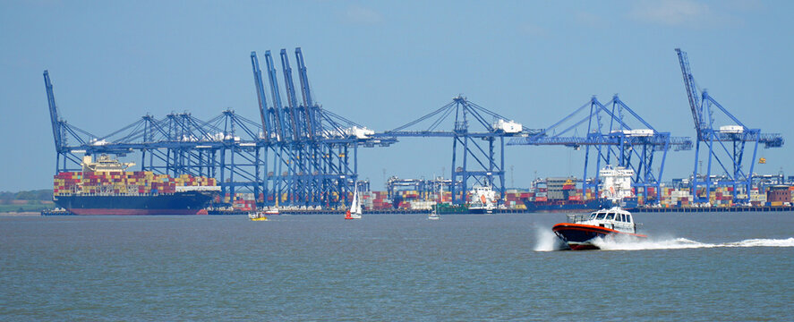 Pilot boat leaving the port of Felixstowe with cranes and container ship in background.