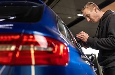 Auto mechanic worker polishing car at an automobile repair and renew service station shop by power...