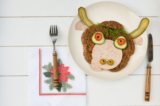 Sandwich iof a cheerful bull made of dark bread, sausages and vegetables 