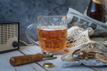Beer in a mug and bottles and a vobla in a string bag on the table. Still life in vintage style.