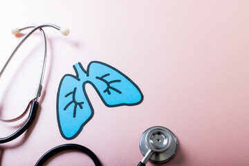 Directly above shot of blue paper lungs with stethoscope against pink background, copy space