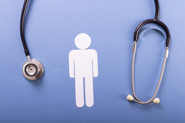 Directly above shot of stethoscope with paper man against blue background, copy space