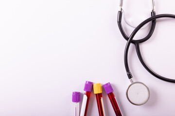 Directly above shot of stethoscope and test tubes with blood over white background, copy space