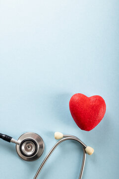 Directly above shot of red heart shape with stethoscope against blue background, copy space