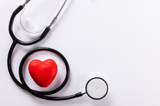 Directly above shot of red heart shape with stethoscope against white background, copy space