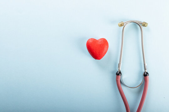 Directly above shot of stethoscope with red heart shape against blue background, copy space
