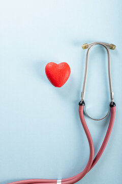 Overhead view of stethoscope with red heart shape against blue background, copy space