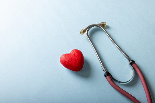 High angle view of stethoscope with red heart shape against blue background, copy space