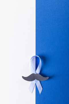 Overhead view of paper mustache and blue prostate cancer awareness ribbon on white, blue background