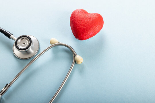 High angle view of red heart shape with stethoscope against blue background, copy space