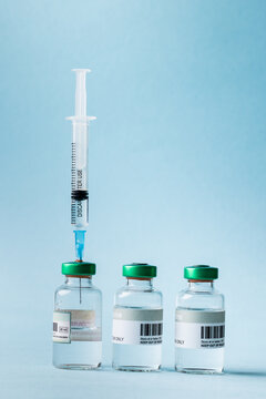 Close-up of syringe and vials arranged against blue background, copy space