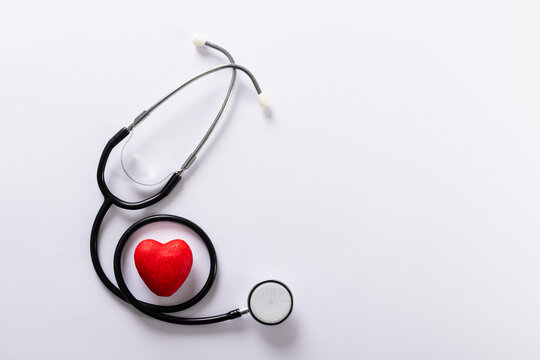 Directly above shot of stethoscope with red heart shape against white background, copy space