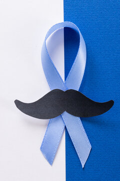 Close-up of paper mustache and blue prostate cancer awareness ribbon on white and blue background