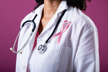 Midsection of african american mid adult doctor with breast cancer awareness ribbon and stethoscope