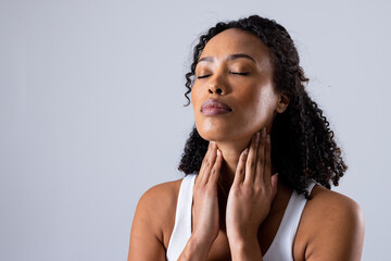 African american mid adult woman with eyes closed touching painful throat against white background