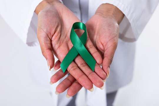 Midsection of african american mid adult female doctor with green mental health awareness ribbon