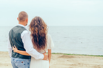 man and woman standing on the shore and looking at the sea