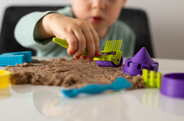Boy is playing kinetic sand indoors