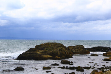 Smooth waves on sea reaching to rocky shore.