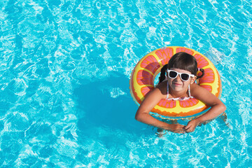close-up portrait of a toddler girl 4 years old swims in the pool in the summer in an inflatable circle and looks at the camera, vacation concept