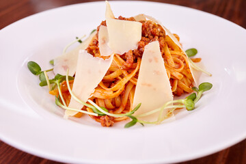 pasta with cheese, microgreens and sauce on a white plate