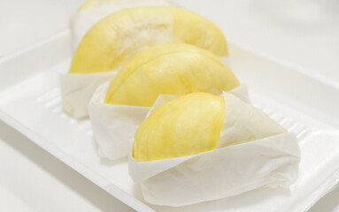 Fresh durian in packaging on wooden dish with durian peel