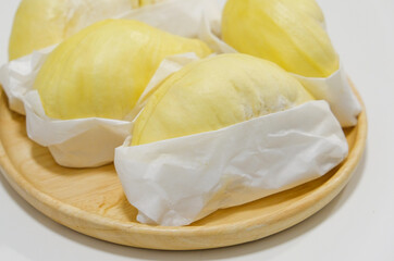 Fresh durian in packaging on wooden dish with durian peel