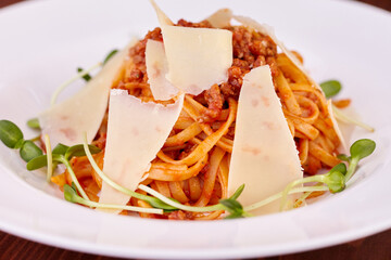 pasta with cheese, microgreens and sauce on a white plate