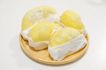 Fresh durian in packaging on wooden dish with durian peel
