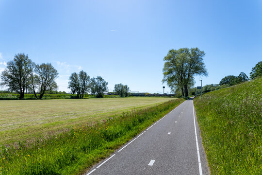 A neatly 2 lane asphalted cycle path along the A44 and the meadows towards Sassenheim train Station in the South-Holland municipality of Teylingen on a sunny day in the Netherlands.