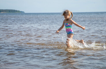 Girl of European appearance having fun in water on the beach and splashing
