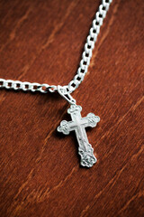 Metal orthodox cross. Silver jewelry isolated on wood. Catholic religion symbol background....