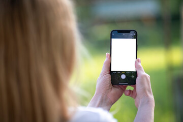 Woman holding phone and taking pictures. Blank screen