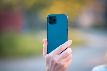 Hand holding blue smartphone. Back side of the phone