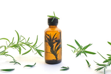 Essential oil of rosemary in a bottle on a white background with fresh sprigs of the plant. natural essential oil
