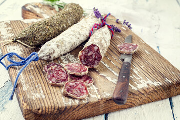 Traditional French salami with camembert and lavender as finger food on a wooden tray - vintage