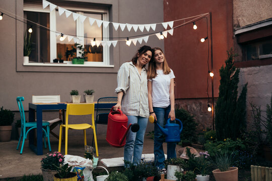 Teenager Girl And Her Mom Gardening Houseplants In Backyard