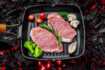 Raw steak with vegetables and herbs on a grill pan. Organic meat