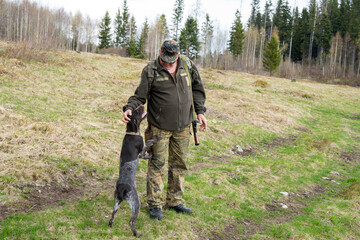 Old Hunter in the woods with his dog. Male hunter hunting with his hunting dog outdoors. German...