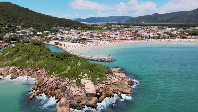 Aerial drone image of paradisiacal rocky shore with atlantic forest and beach in the background with tourists enjoying the beach and sea rocks and soft ocean access by boats mountain