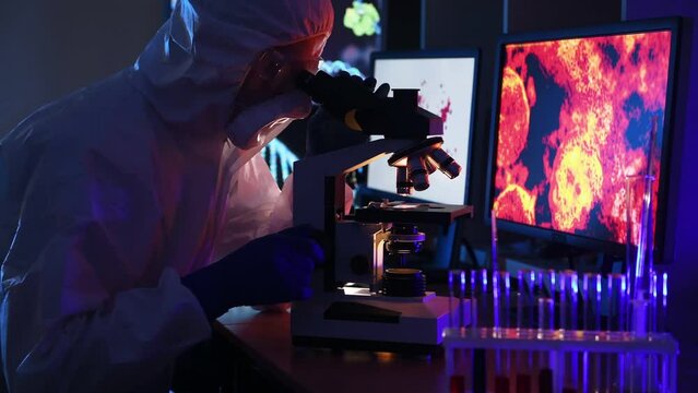 Worker in lab coat is working with virus under microscope
