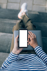 Young woman freelancer working online using her laptop, sitting on stairs.