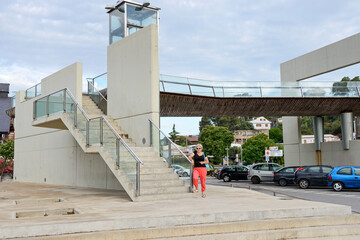 Aged lady is standing near footbridge in Santa Susanna, Spain.