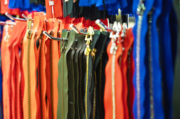 Fototapeta premium Group of zippers hangs on rack with hooks at exhibition