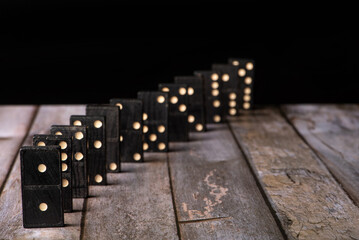Dominoes, old domino pieces lined up on wooden surface, dark background, selective focus on first...