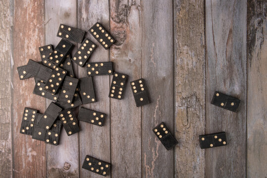 Dominoes, old domino pieces played randomly on wooden surface, dark background, top view.